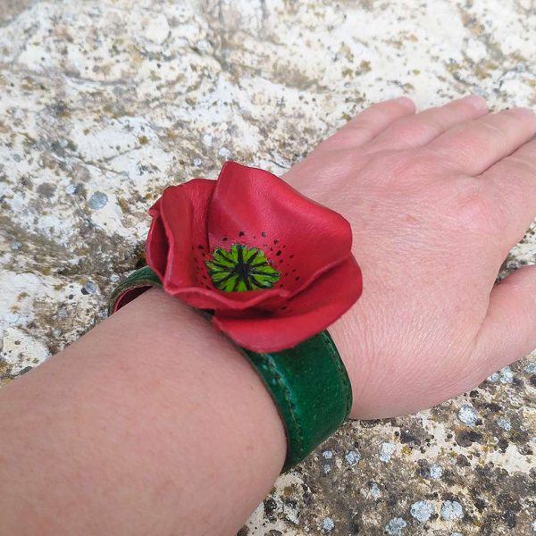 Mano y muñeca con pulsera flor eterna tipo amapola roja de cuero para comprar